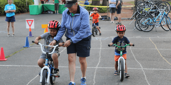 A PE instructor helps two young students learn to ride bikes in Cascade's Leto's Go.